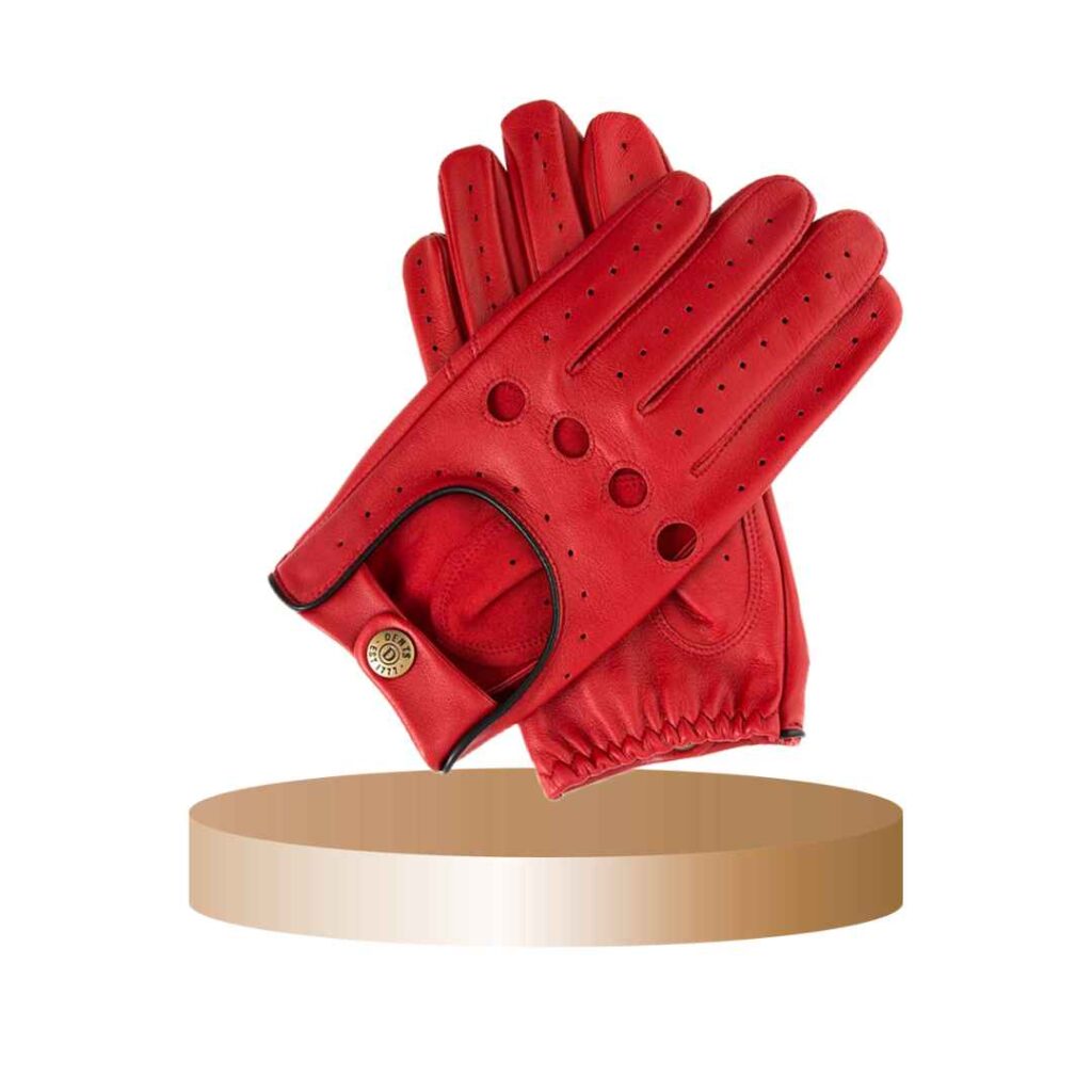 Pair of red leather driving gloves with black trim and button closure displayed on a round platform.